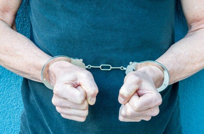 Torso view of Caucasian man with hands in handcuffs against a black shirt - edmundson class action, wrongful incarceration