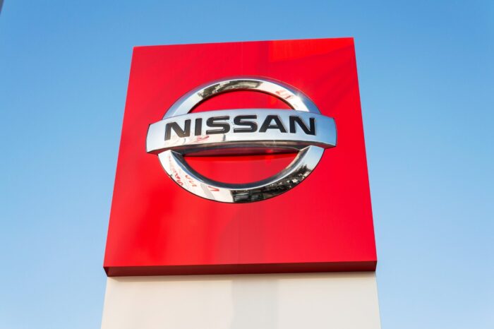Nissan motor company logo in front of dealership building