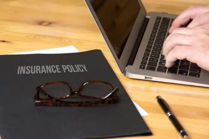 computer and a folder with insurance policy, insurance settlement