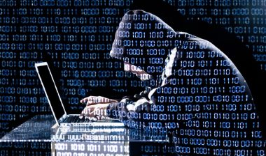 timios data breach concept, image of hooded man leaning over laptop