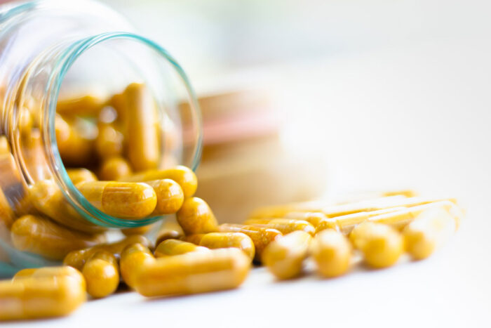 Close up of supplement capsules spilling from glass container onto white surface - Labrada supplements class action lawsuit