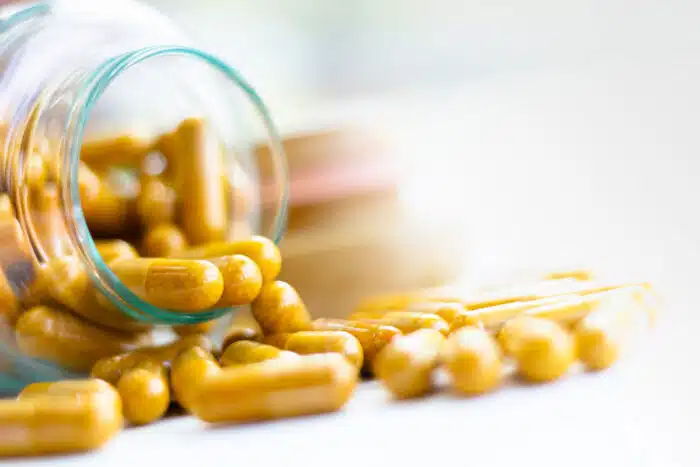 Close up of supplement capsules spilling from glass container onto white surface - Labrada supplements class action lawsuit
