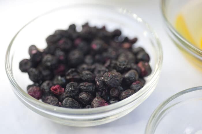 Freeze dried blueberries in a bowl on a white background.