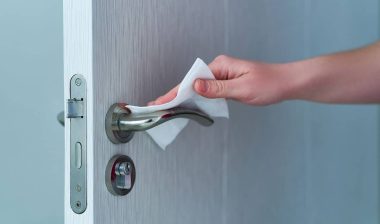 Person disinfects and cleans door handle with antibacterial wet wipes to protect against viruses, germs and bacteria.