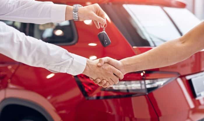 handing keys while sealing deal in car dealership - Falls Motor City misleading ads, false advertising