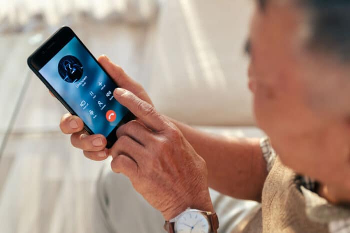 Old man accepted call with unknown person by smart phone at home - scam calls, auto warranty