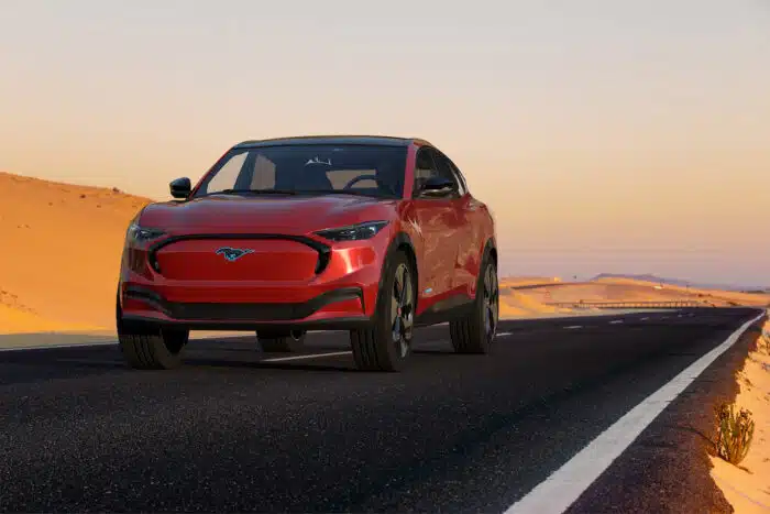 Ford Mustang Mach-e driving along an isolated desert paved road.