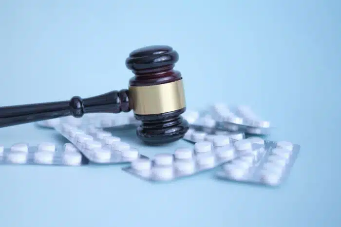 Gavel and pills on a blue background.