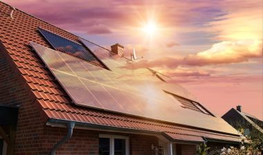 solar panels, photovoltaics on the red roof of a house and a beautiful sky with the setting sun.