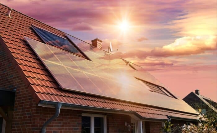 Solar panels, photovoltaics on the red roof of a house and a beautiful sky with the setting sun - Sanyo and Panasonic solar class action lawsuit settlement, solar panel delamination