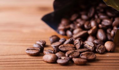 Close up of coffee beans spilling out of a bag onto a wood surface, representing Starbucks class action lawsuits