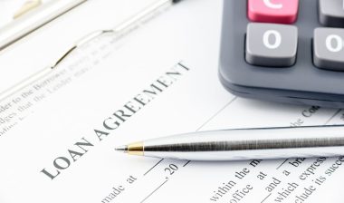 Blue ballpoint pen and a calculator on a loan agreement; tribal loans