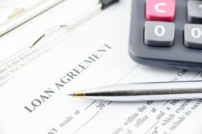 Blue ballpoint pen and a calculator on a loan agreement - tribal loans, silver cloud financial lawsuit