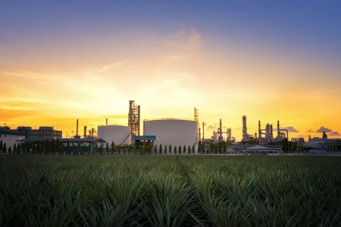 Natural Gas storage tanks in a field against a sunset sky.