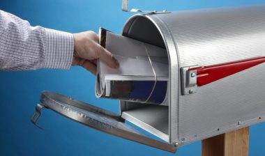 Man takes out mail at an open mailbox