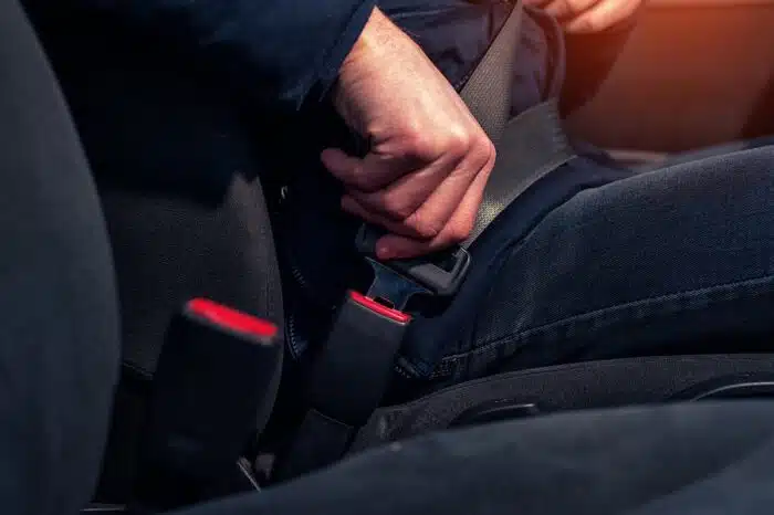 Cropped shot of male hand fastening seat belt in the car. Auto seatbelt safety concept.