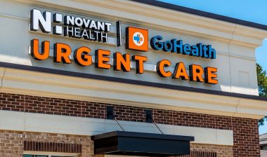 Close up of "Novant Health" Urgent Care facility's exterior facade brand and logo signage on a sunny day with clear blue sky.