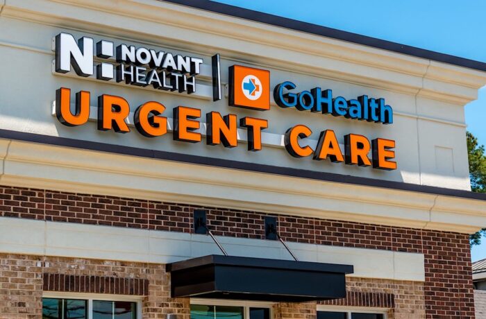 Close up of "Novant Health" Urgent care facility exterior facade branding and logo on a sunny day with clear blue sky.