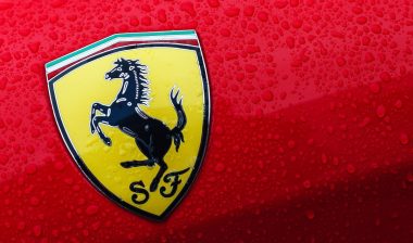 A close-up of the Ferrari logo on a red car with drops of water.
