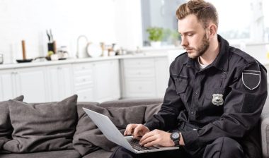 officer sitting on couch and typing on laptop keyboard; Colorado Department of Corrections lawsuit concept.