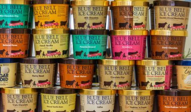 Various tubs of Blue Bell ice cream stacked on top of each other.