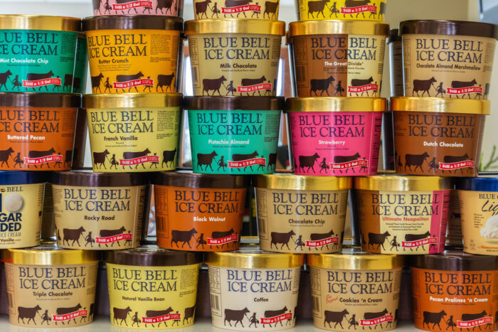 Various tubs of Blue Bell ice cream stacked on top of each other.