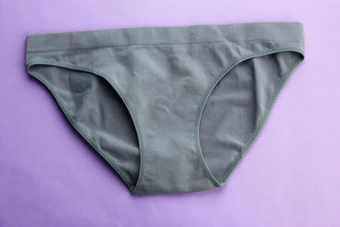 Close up of womens gray underwear on a purple background.