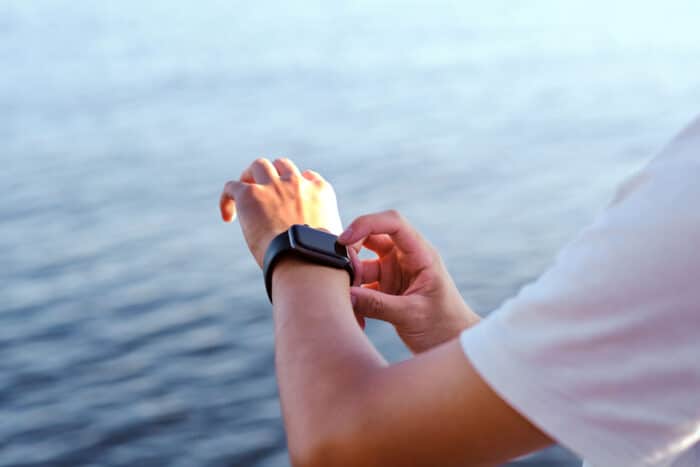 Youth is using an Apple Watch against abstract blue wave water background.