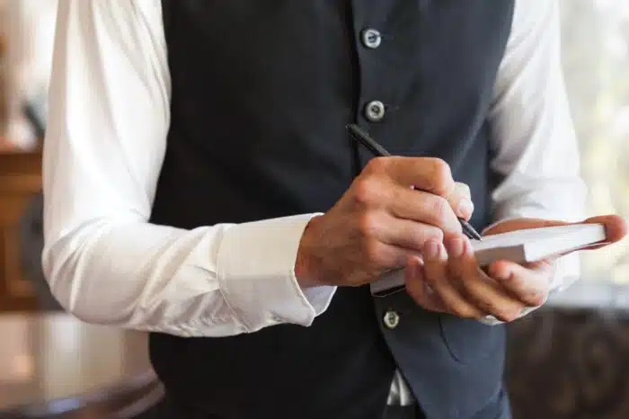 Waiter taking an order wearing a waistcoat in a fancy restaurant, san jose restaurant