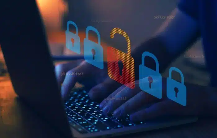 A person uses a laptop in a dark room, with padlock graphics overlaying the image - hacker attack, cyber crime concept, GCPA settlement, Gastroenterology Consultants PA