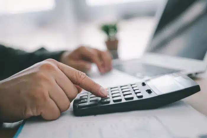 Close up of a mans hands using a calculator. Credit reporting fees concept.