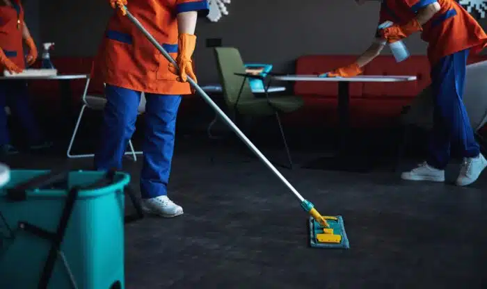 Three female janitors in rubber gloves doing the wet cleaning - wage settlement, lawsuit