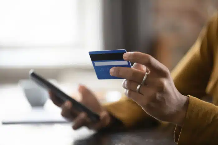 Close up of woman's hands holding credit card and smartphone. Paying bill over the phone concept.