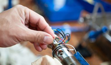 An electrician's hand is choosing the electricity wire of electronic equipment. Industrial working scene, close-up and selective focus.