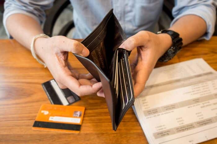Close up of a mans hands holding a brown wallet - credit card, household debt