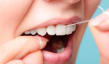 Close up of a woman using dental floss.