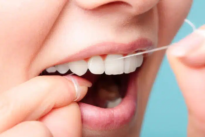 Close up of a woman using dental floss.