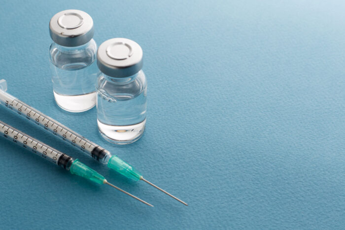 Syringes, glass medicine vials on a blue background - remicade class action lawsuit, johnson & johnson, settlement, janssen biotech, infliximab