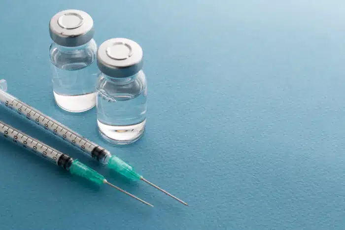 Syringes, glass medicine vials on a blue background - remicade class action lawsuit, johnson & johnson, settlement, janssen biotech, infliximab