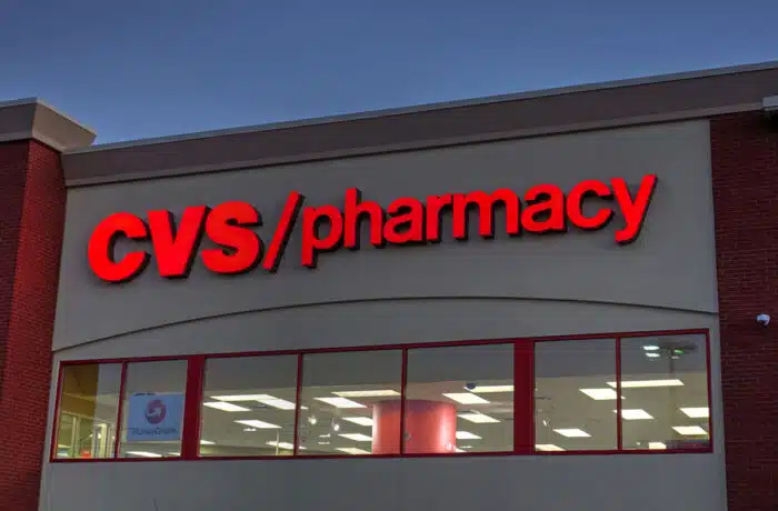 Close up of CVS pharmacy signage on exterior of building against a dark blue sky.