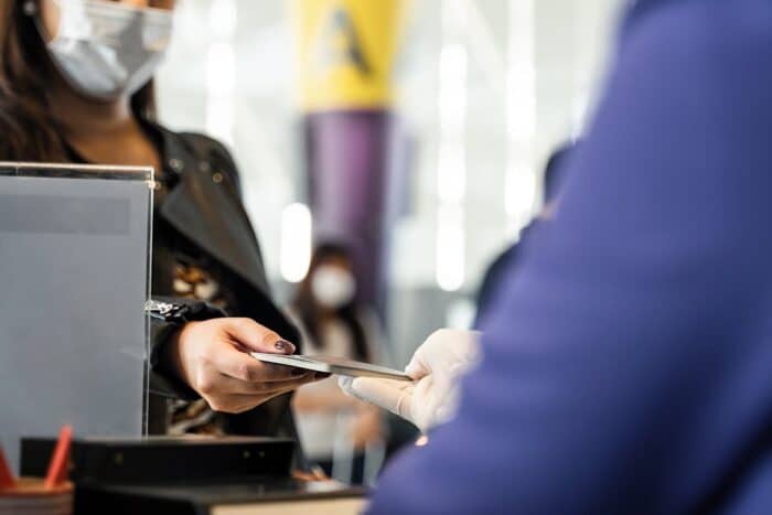Close up of female traveler giving passport to customer check in officer at airline service counter.