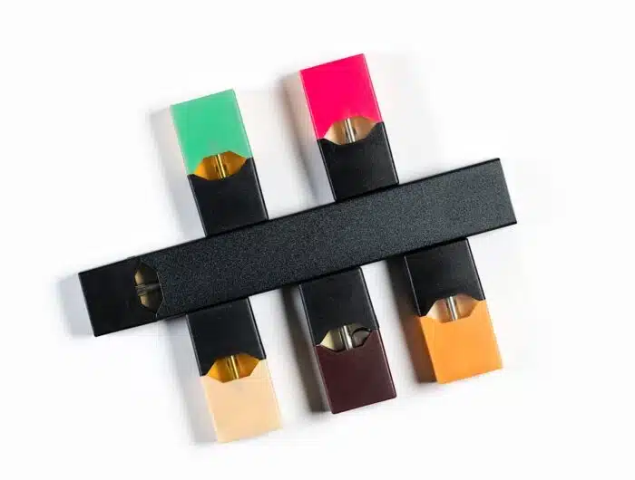 E-cigarette or nicotine vapor stick and flavor dispensers on white background.