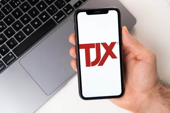 Close up of a man’s hands holding a smartphone with the TJX logo displayed.