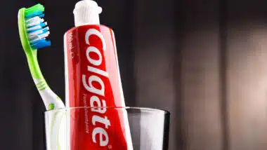 Close up of Colgate toothpaste with a toothbrush in a glass jar.