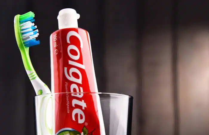Close up of Colgate toothpaste with a toothbrush in a glass jar.
