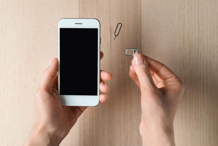 Woman inserting sim card into mobile phone, close up.