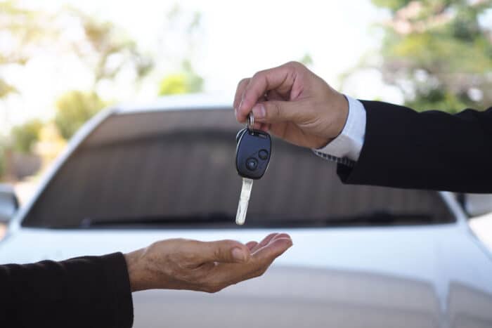 Close up of a car salesman's hands giving keys to another.
