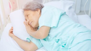 Asian woman wearing green pajamas lying on the bed in a room