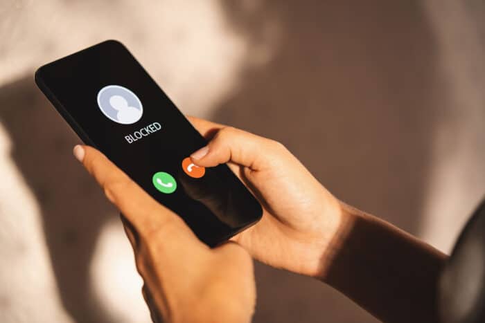 Close up of a woman's hands holding a smartphone receiving a call from an unknown number.