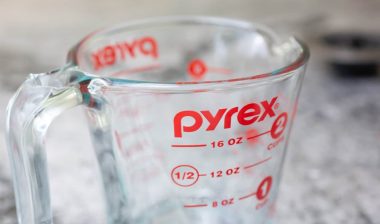 A closeup view of a Pyrex measurement cup glass on the kitchen counter.